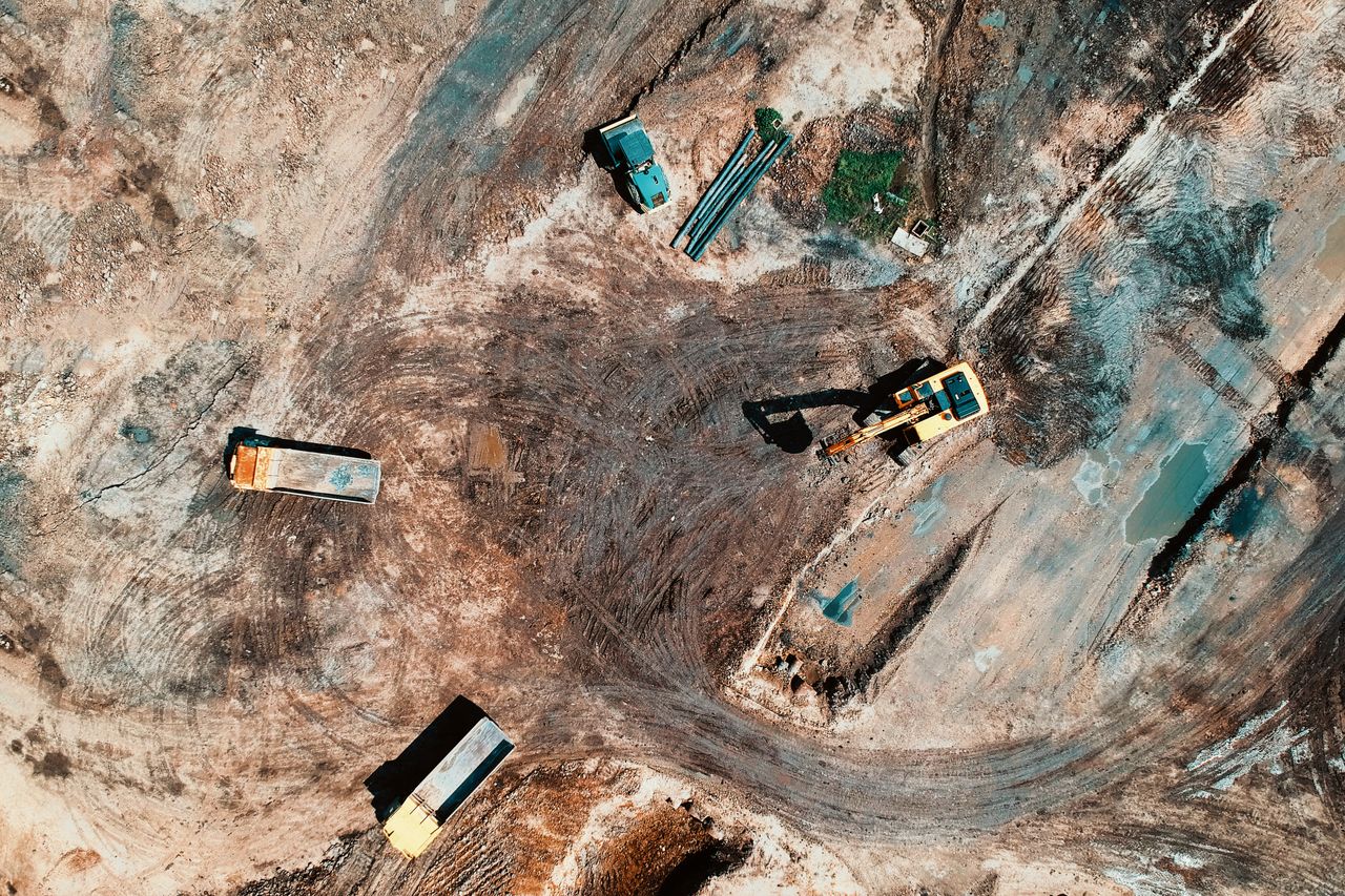 Services High-angle aerial view of construction site with earthmoving equipment and trucks.
