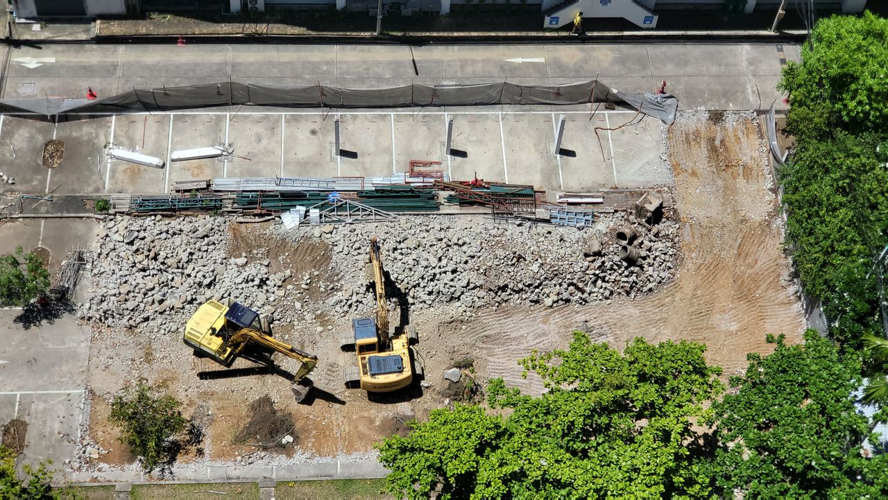 Services Aerial shot of an urban construction site with excavators moving debris and dirt.
