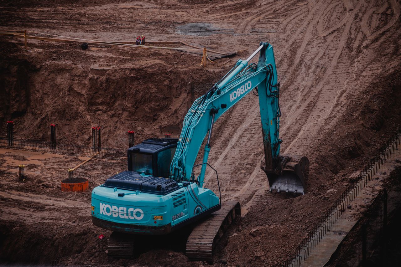Services Blue excavator digging a pit at a construction site in Vilnius, Lithuania.