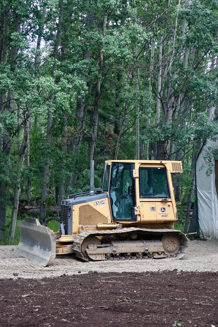 Services Yellow bulldozer in forest clearing preparing soil for landscaping project.