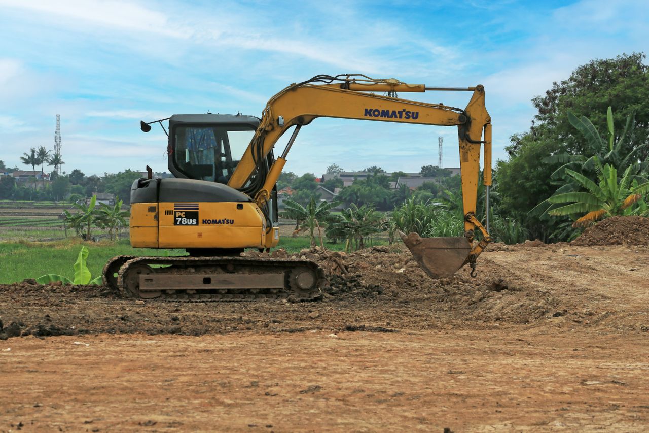 Services Yellow excavator on a rural construction site on a sunny day.